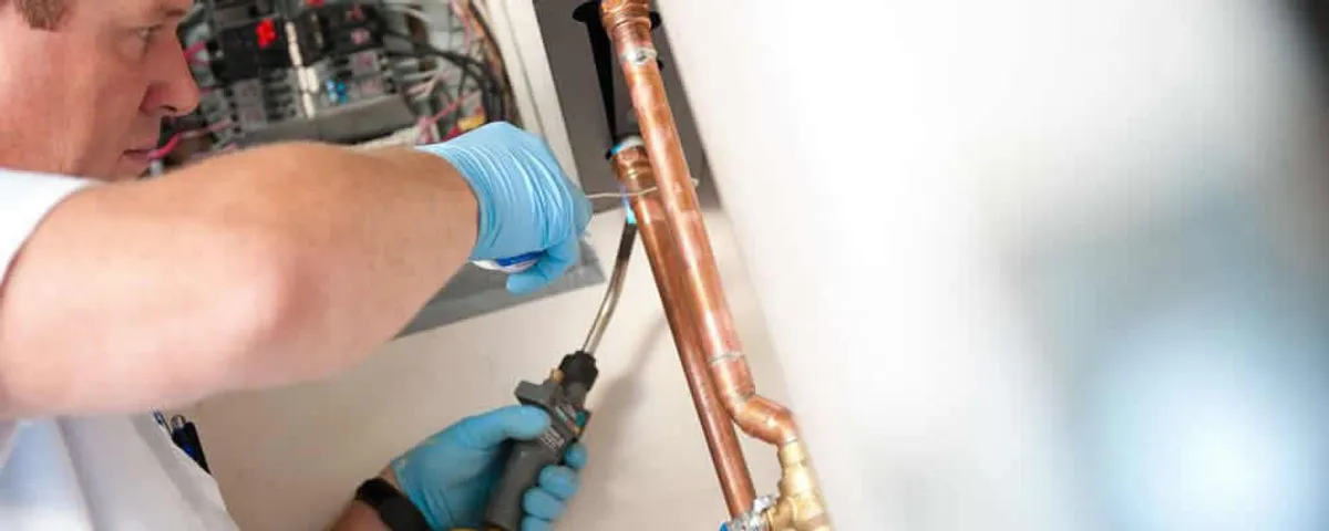 Water heater repair technician testing copper pipe connections and controls in Las Vegas, NV